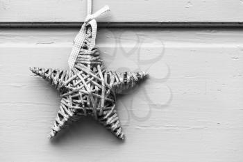 Wicker star hanging on white wooden wall, outdoor Christmas decoration. Black and white  background photo
