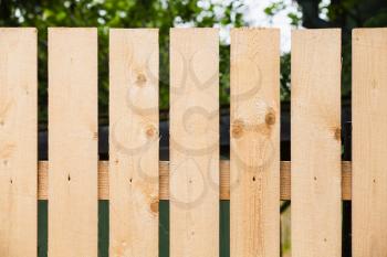 Fragment of new wooden fence in summer garden