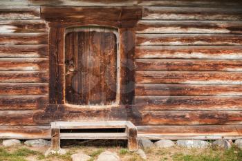 Small closed door in wall made of rough logs. Traditional rural Russian architecture details