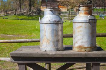 Two metal milk churns stand on wooden table