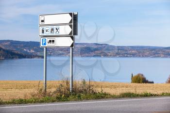White information road sign stands near rural European highway