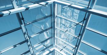 Abstract contemporary architecture background, internal structure of glass roof arch with lockable windows sections. Blue toned photo