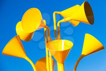 Group of bright yellow loudspeakers over blue sky background