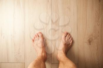 Male feet stand on wooden floor, top view