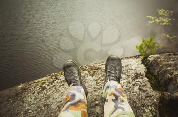 Male feet in camouflage pants and black rough shoes. Travel lifestyle background. Vintage warm tonal correction photo filter, old style effect