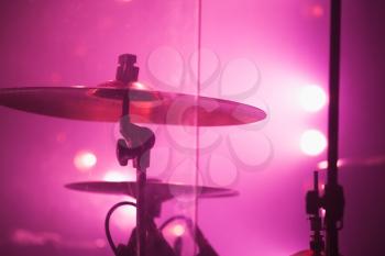 Live music photo background, rock drum set  with cymbals in red stage lights. Closeup photo, soft selective focus