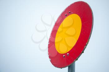 Round red and yellow stop sign on metal pole over bright blue sky