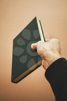 Male hand holds dark green book, vintage toned photo with selective focus