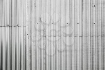 Gray corrugated metal fence made of sheets with bolts, industrial wall background photo texture
