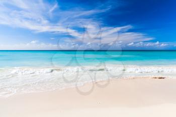 Tropical beach background, white sand and azure shore water under cloudy blue sky. Caribbean Sea coast, Dominican republic, Saona island