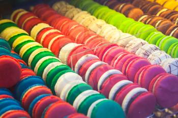 Assortment of colorful traditional French macarons lays in raow on market counter