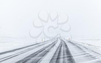 Icelandic road covered with snow, empty rural landscape