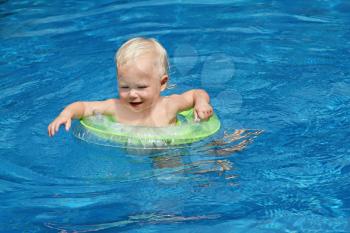 Baby swimming in the blue pool water