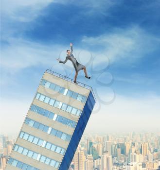 Businesswoman balancing on the top of the falling high builging against the city