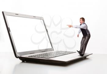 Afraid man stands on the edge of  laptop and points to monitor