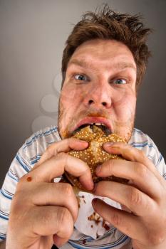 Portrait of expressive fat man chewing hamburger