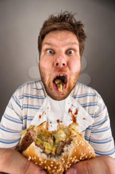 Portrait of surprised dirty man chewing hamburger