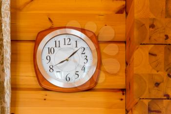 Wooden clock hanging on the wooden wall close up