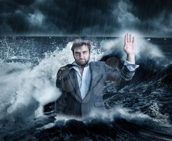Wet businessman standing in the sea while storming
