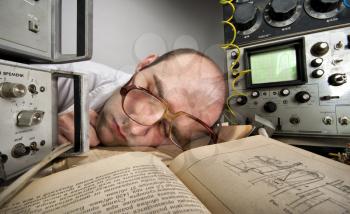 Exhausted scientist sleeping on book at vintage technological laboratory
