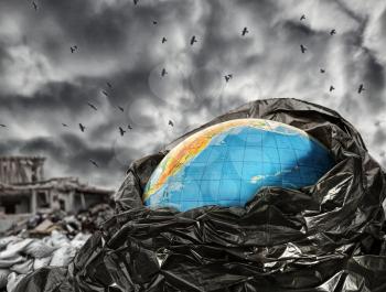 Earth globe in trash against dramatic sky