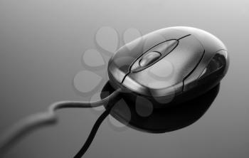 Computer mouse on reflective grey surface. In B/W