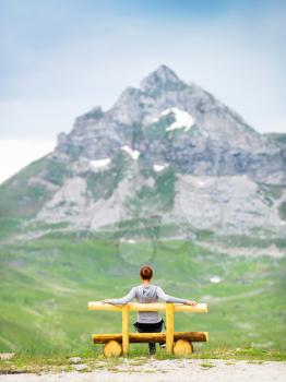 Girl is sitting on the bench in mountain landscape. National Park Durmitor, Montenegro, Europe