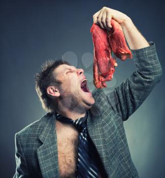 Crazy businessman eating raw meat