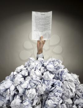 Hand with Agreement reaches out from big heap of crumpled papers