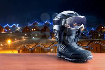 One black snowboarding boot with helmet and mask standing on country background