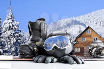 Winter sport glasses, snowboarding boot, helmet and gloves on winter mountains background