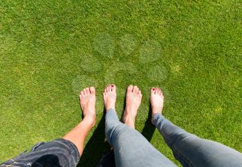Two pairs of bare feet standing on the grass