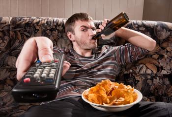 Man with beer and chips watching TV at home