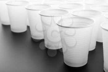 Lots of white plastic drinking glasses on grey background