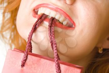 Shopping bag in woman's smiling mouth