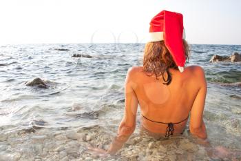 Tan woman in christmas hat in sea