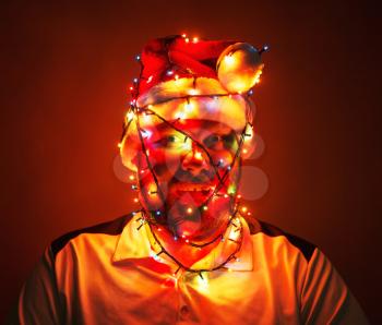 Man wrapped in xmas lights sitting in the dark