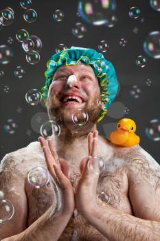 Happy man taking bath and applauding for soap bubbles
