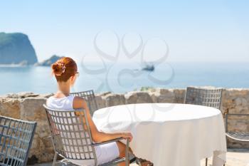 Girl is sitting infront sea view terrace of the luxury hotel of Montenegro with mountain view