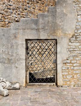 Arched old lattice door in a stone wall
