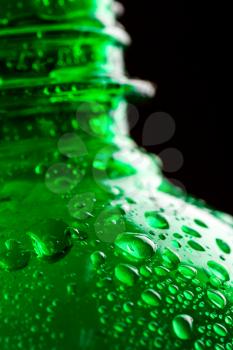 Green wet plastic water bottle closeup on black background