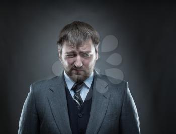 Sad businessman agaist dark gray background