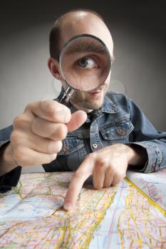 Funny nerd tourist discovering map with magnifier