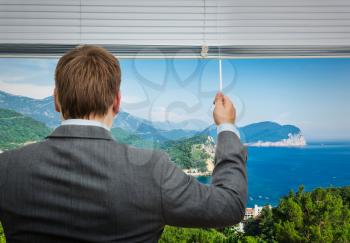 Businessman is looking through the window with sea view