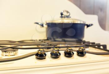 Stove with saucepan on the white modern kitchen closeup