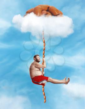 Fat happy man hanging on the sausage rope in the sky