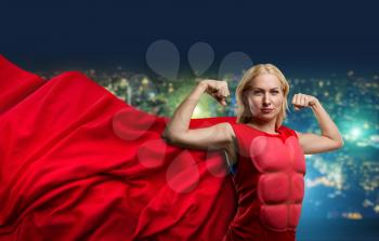 Strong woman superhero showing off her strength against night city background