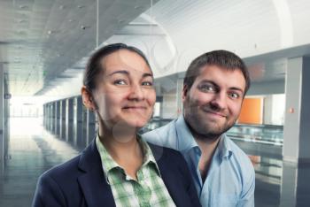 Businessman and businesswoman stand smiling in the office