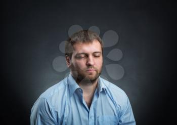 Man wearing blue shirt dreaming with closed eyes over black