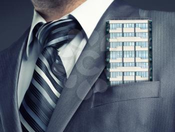 Businessman with office building in suit pocket
